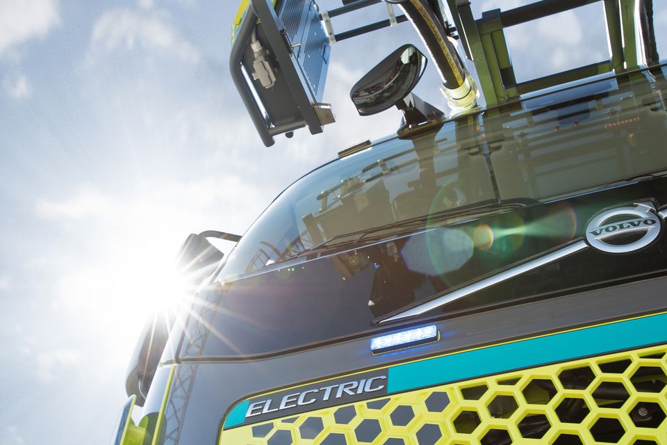 L32A XS electric: Detail Front und Drehleiter angeschnitten Nahaufnahme von vorne unten des Drehleiterfahrzeuges. Im Fokus der Schriftzug ELECTRIC und angeschnitten die Drehleiter.