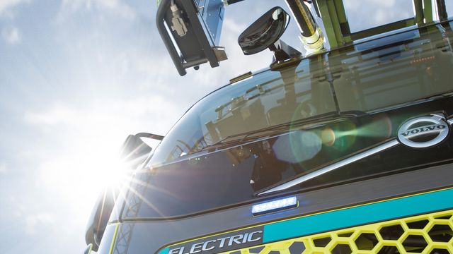 L32A XS electric: Detail Front und Drehleiter angeschnitten Nahaufnahme von vorne unten des Drehleiterfahrzeuges. Im Fokus der Schriftzug ELECTRIC und angeschnitten die Drehleiter.