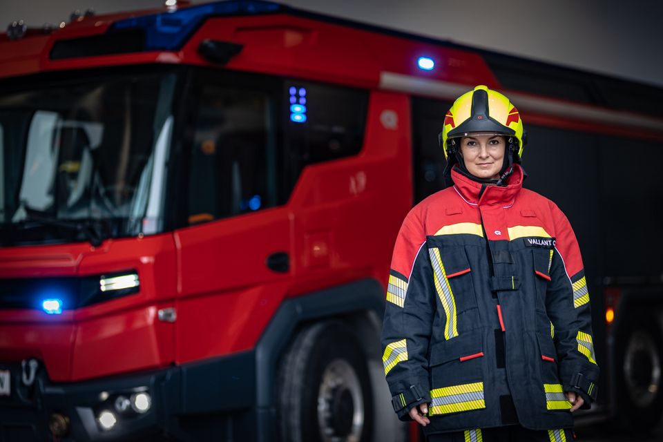 RT: Feuerwehr in voller Schutzausrüstung Rechts im Vordergrund eine Feuerwehrfrau in voller Schutzausrüstung, dahinter unscharf der RT.